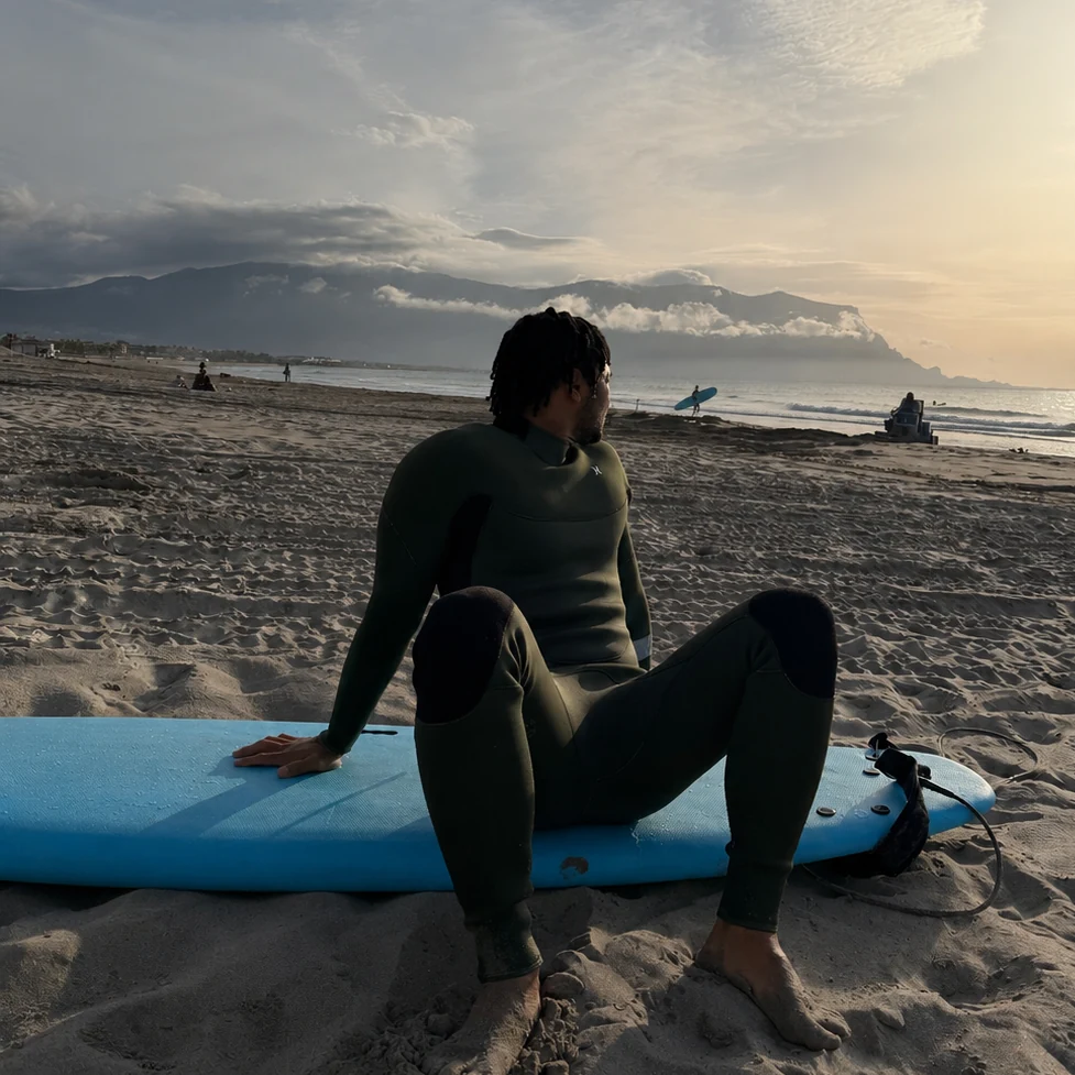 Crypto Seth sitting on a surfboard at sunrise